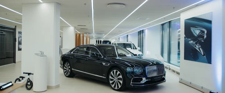 Bentley showroom i Stockholm med svart lyxbil upplyst i en modern, stilren miljö med ljusa ytor, stora fönster och designinslag längs väggarna.
