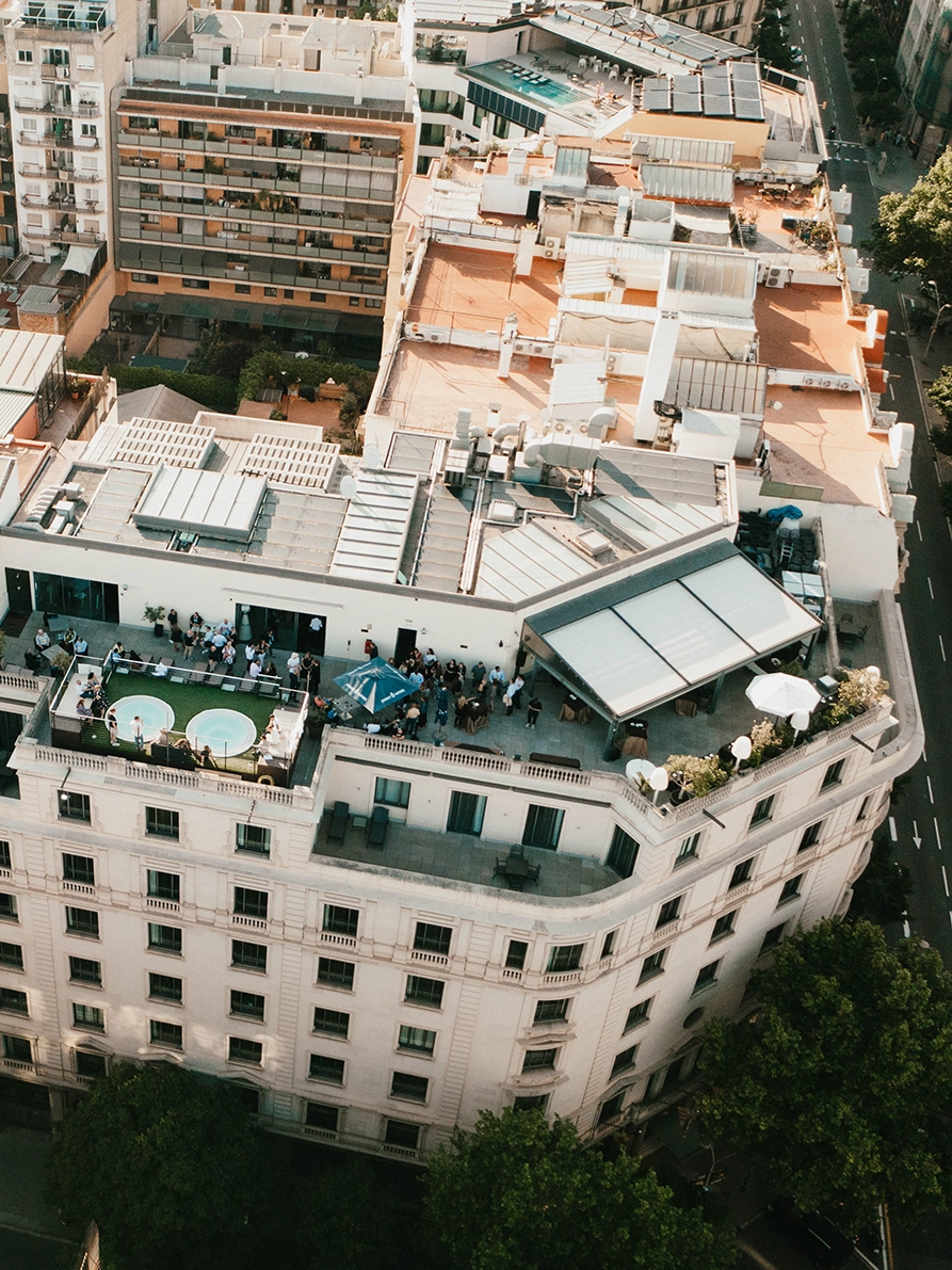 Flygvy över takterrass i Barcelona med pool, minglande konferensdeltagare och utsikt över stadens byggnader under ett event för Fastighetsägarna Service
