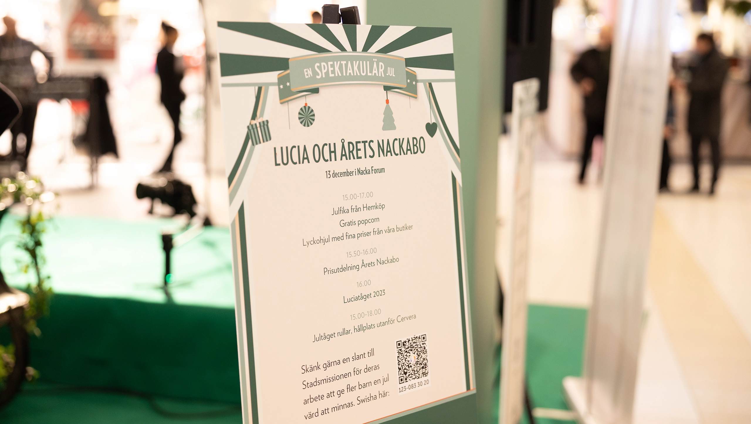 Skylt i Nacka Forum med program för Luciafirande och Årets Nackabo – del av julkampanjen “En spektakulär jul” med eventinformation och tider.