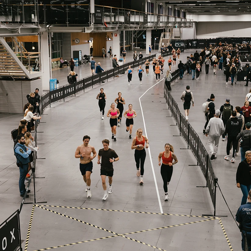 HYROX Stockholm i mässhall med löpbanor, publik och tävlande – ett internationellt fitnessrace och stort sportevent med branding och eventproduktion i arenamiljö.
