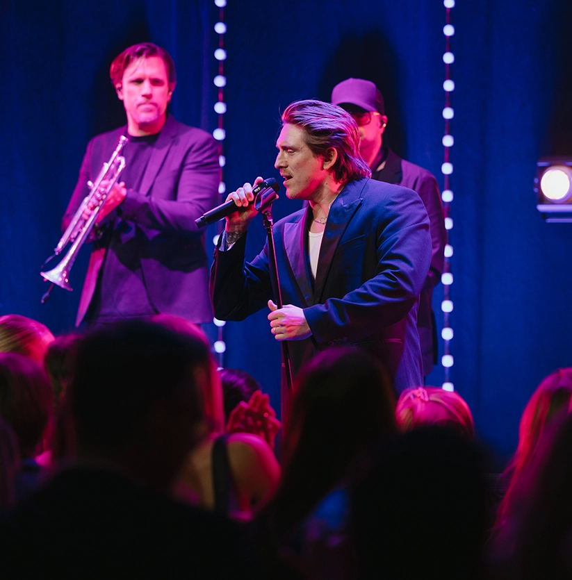 Danny Saucedo uppträder live på scen under Guldhemmet-galan med publik framför scenen och band i bakgrunden
