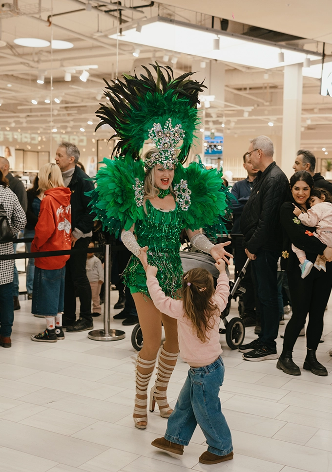 Sambadansare i grön kostym interagerar med barn och besökare i Mall of Scandinavia under The Body Shops 50-årsjubileum.