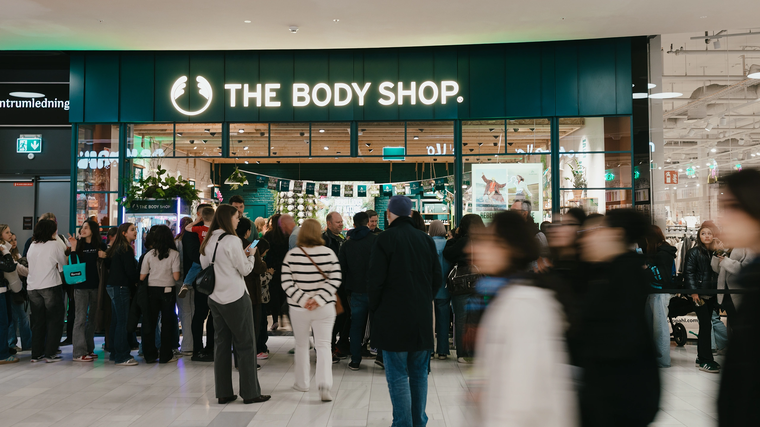 Folksamling utanför The Body Shop i Mall of Scandinavia under 50-årsjubileum, med kö in till butiken och livlig atmosfär under eventaktivering.