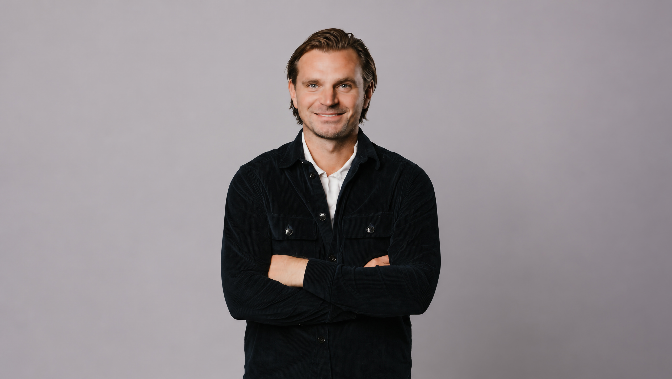 Niklas Åström, vd och grundare av K&E Studios, med armarna i kors framför en grå bakgrund.